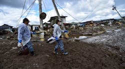 Workers walk past damaged homes and debris littering the area near where a river burst its banks in Nagano on Oct. 15, 2019, after Typhoon Hagibis hit Japan.