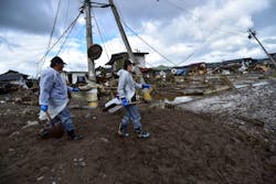Workers walk past damaged homes and debris Workers walk past damaged homes and debris
