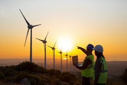 Engineers pointing at a range of wind turbines Engineers pointing at a range of wind turbines