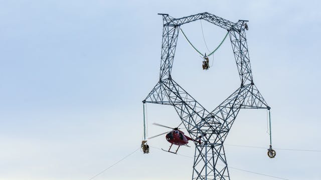 A helicopter guided wire through pulleys. Once the first phase of stringing was finished, the small-gauge cable was attached to another thicker cable and pulled back through the pulleys. The thicker cable was used to pull the final conductor into place.