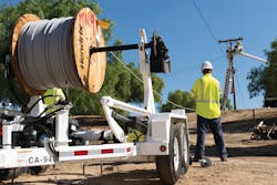 A large spindle of covered conductor rolls out as SCE linemen in bucket trucks replace bare wire with the new lines, which help mitigate the threat of wildfires.