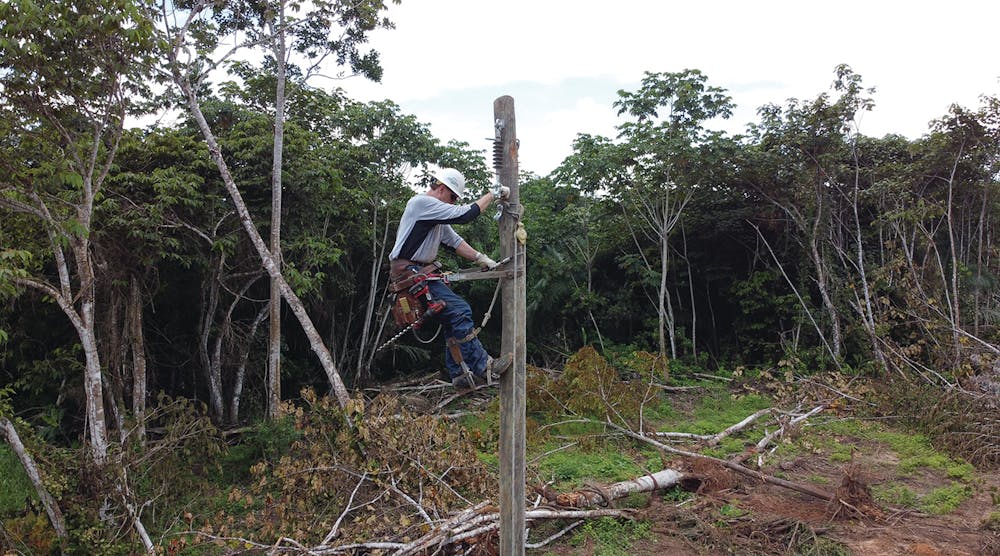 Lineman Mike Teter climbs the first of 94 poles that would be used to reach Villa Cotoca in Bolivia.