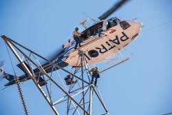 Aerial line workers descend from aircraft onto transmission tower to conduct inspection. Aerial line workers descend from aircraft onto transmission tower to conduct inspection.