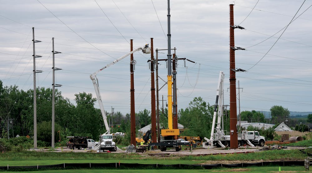 Three Phase Line crews maneuver equipment situated atop timber mats into position to pull new wire and attach it to new steel transmission structures.