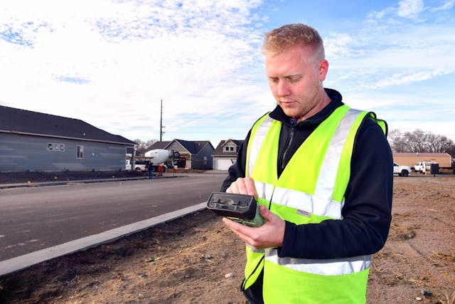 Brian Kraegenbrink, distribution designer trainee, uses a cellphone and other devices to tap into the UEC mapping system while working in the field.