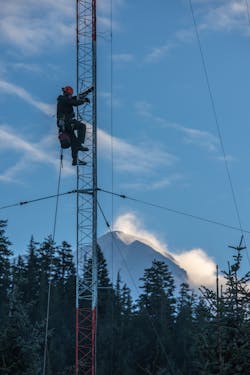 A worker climbs a radio tower to replace an electric light in Cordova, Alaska.