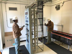 Riviera team members Ray Norris (left) and Jack Resmondo (right) inspect a transformer protection panel inside a substation control house. Resmondo is capturing photos of relay wiring to store in the equipment details of eSMART for reference.