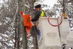 A lineworker uses a rubber blanket to protect himself from energized lines.