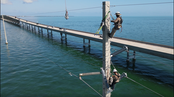 A barehand crew member prepares new hardware and the polymer for overhead installation.