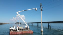 The barehand truck holds the 138-kV phase while crew members on the structure remove the old and install new polymers. The barehand truck holds the 138-kV phase while crew members on the structure remove the old and install new polymers.