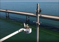 The crew on the structure secures the final new insulator on the structure. The crew on the structure secures the final new insulator on the structure.