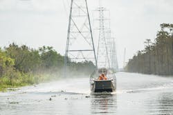 Linemen access damaged transmission structures in a swampy area near Orange, Texas, in a fan boat.
