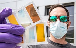Lance Wheeler holds a perovskite window prototype, which demonstrates the variety of colors that can be obtained.