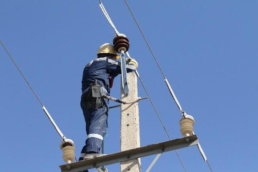 A lineman in Iran installs conductor covers on all three phases to prevent phase-to-ground contacts by wildlife climbing, perching, or roosting on the electric distribution system.