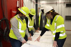 Inside the STATCOM, Project Manager, Suzanne Pohlman (left) and Emily C. McCurren, (right) Transmission Substation Design Engineer, review construction drawings with the project team. Inside the STATCOM, Project Manager, Suzanne Pohlman (left) and Emily C. McCurren, (right) Transmission Substation Design Engineer, review construction drawings with the project team.