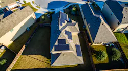 Rooftop solar installations in a residential area. A DERMS provides centralized monitoring and control of DERs connected to a distribution grid by forecasting, monitoring and managing the operation of each DER to satisfy operating and business objectives.