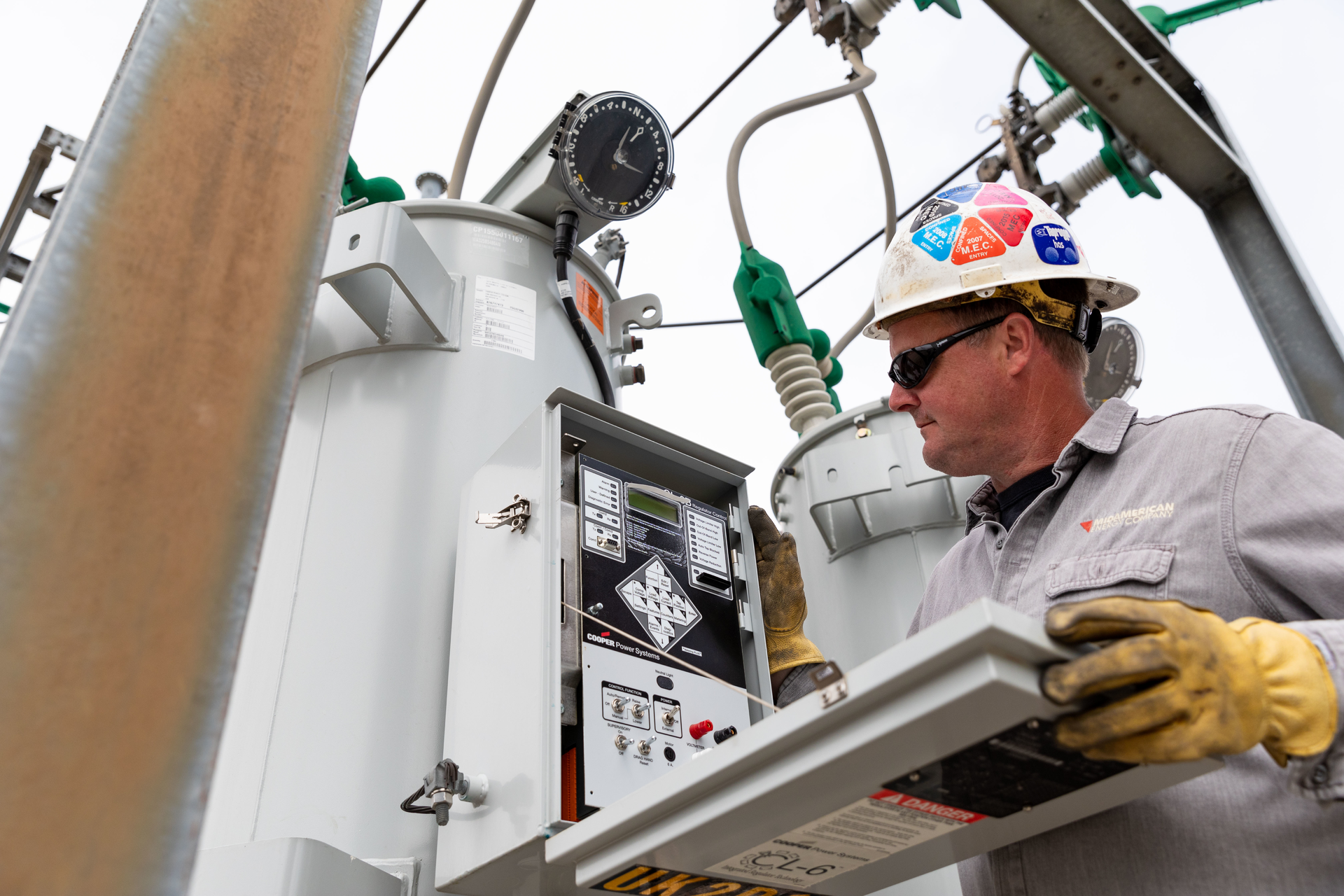 A substation technician inspects a voltage regulator control.