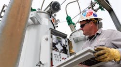 A substation technician inspects a voltage regulator control.