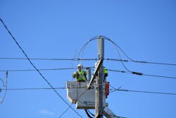 Linesman connecting a covered conductor to a bare conductor interface pole top structure. Linesman connecting a covered conductor to a bare conductor interface pole top structure.