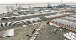 The Port of Esbjerg OSW marshaling port in Denmark (2017). Blades and some tower sections are in foreground. Tower assembly can be seen in background adjacent to load-out areas. For scale, blades pictured are 80 m (262.5 ft) long. Reprinted with permission from the Port of Esbjerg.