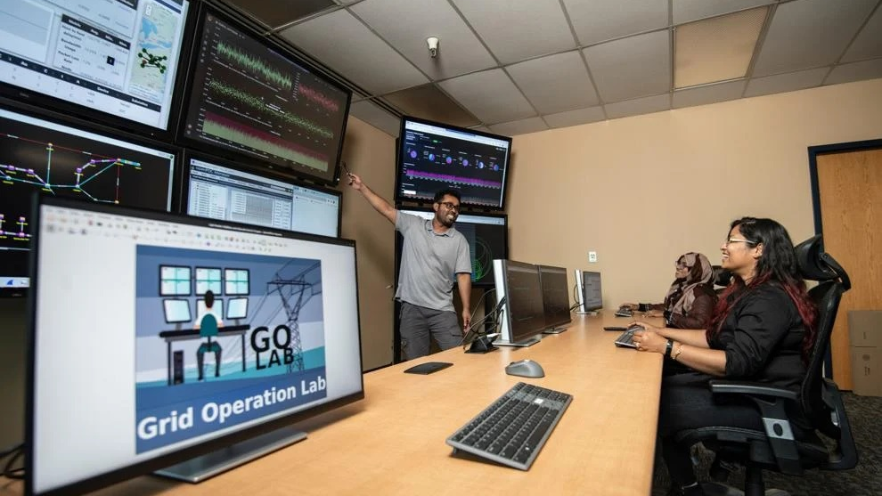 WVU Lane Department of Computer Science and Electrical Engineering students Partha Sarker, Paroma Chatterjee and Jannatul Adan, discuss a power grid simulation project led by Anurag Srivastava, professor and department chair, in the GOLab.
