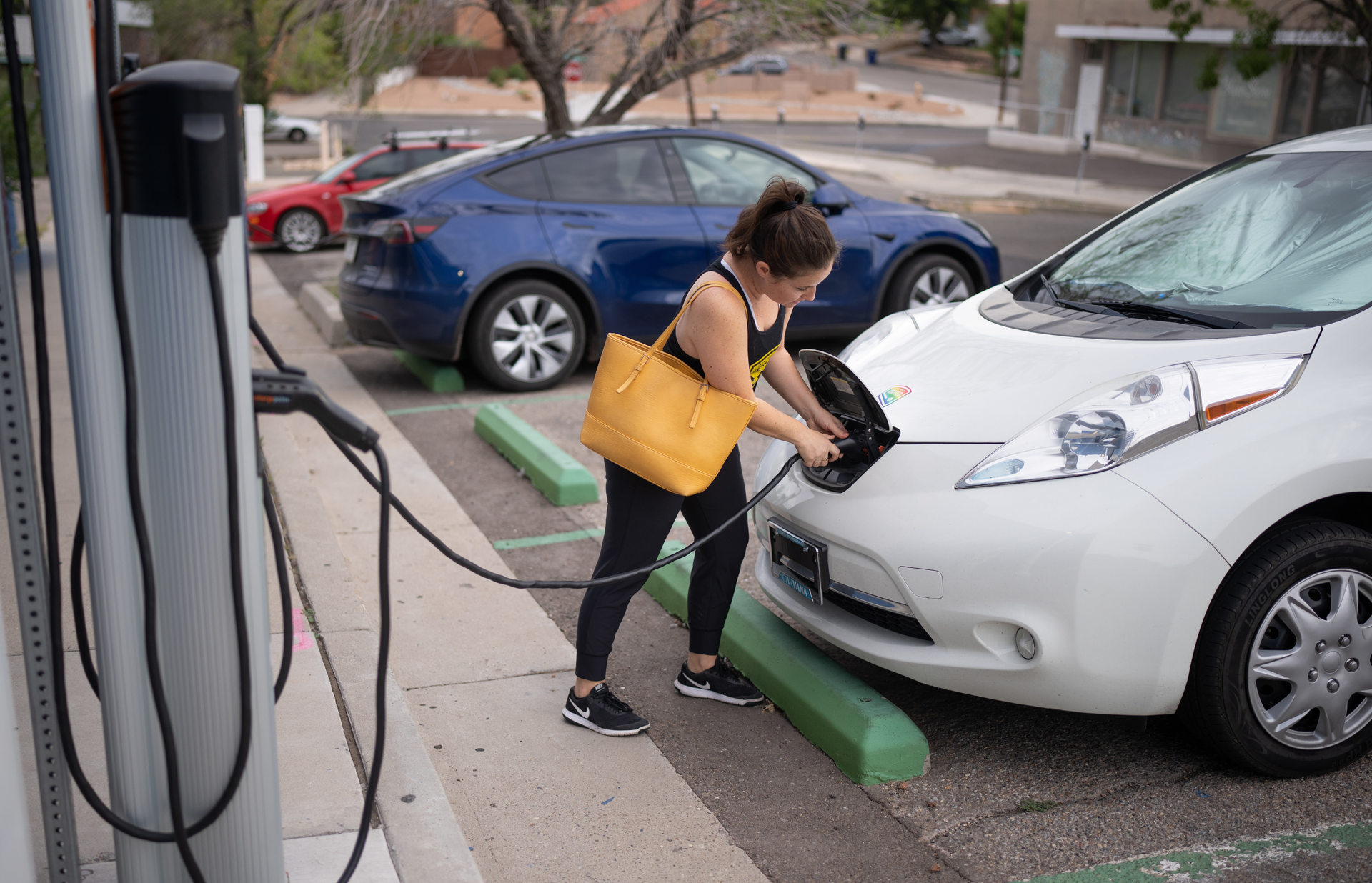 Kaedi Sanchez plugs in her car at a City of Albuquerque electric vehicle charger before heading to work. Sandia National Laboratories researchers have been studying the vulnerabilities of electric vehicle charging infrastructure, including public chargers, to better inform policymakers.