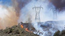 Wildfire sweeps the mountainside, crossing metal transmission towers.