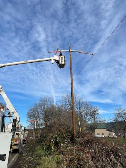 A utility worker clips in a new conductor to a distribution crossarm. Long-term system hardening projects &mdash; including overhead-to-underground conversion, covered wire and intelligent reclosers &mdash; are critical to the reduction of wildfire risk.