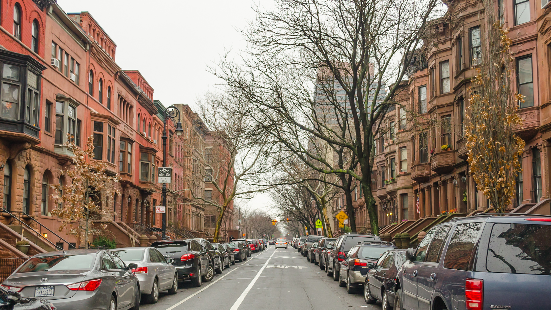 This urban neighborhood shows brown detached houses and a few bare trees.