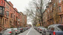 This urban neighborhood shows brown detached houses and a few bare trees. This urban neighborhood shows brown detached houses and a few bare trees.