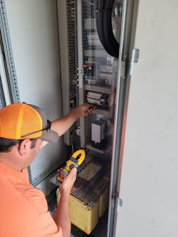 Fox Island Linemen, Joe Bickford, tests the circuitry in one of the wind turbine controls cabinets at the base of the turbine, to determine if a contactor had failed. Fox Island Linemen, Joe Bickford, tests the circuitry in one of the wind turbine controls cabinets at the base of the turbine, to determine if a contactor had failed.