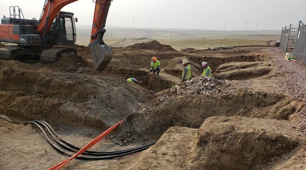 PacifiCorp crews work on underground cables near a functioning wind farm.