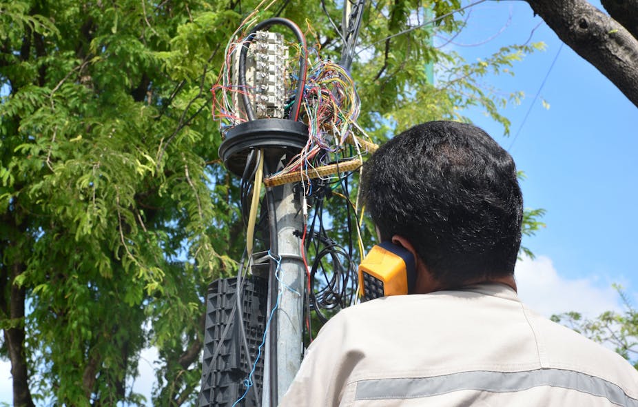 A technician plugs a network cable into a line socket. A robust, private broadband network will help electric utilities build and maintain a real zero T&amp;D grid in the years approaching 2050.