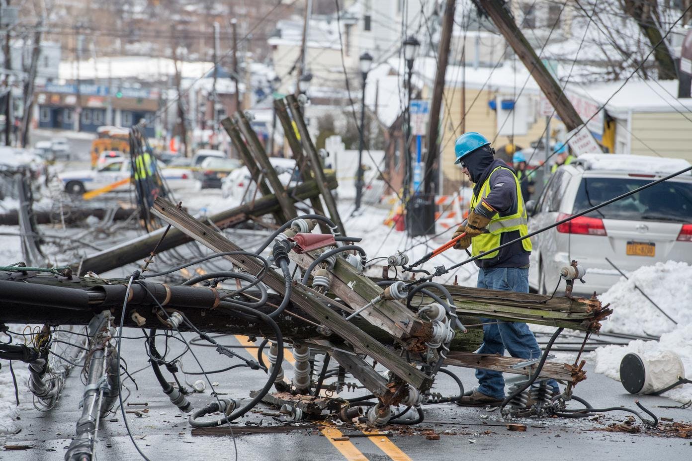 A Con Edison worker with insulated tools approaches a downed distribution pole on a Yonkers street after a storm in March 2018.