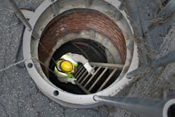 Underground worker enters underground electric vault. Underground worker enters underground electric vault.