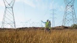 Surveyors inspect transmission lines in a field. Photo from Getty Images Surveyors inspect transmission lines in a field. Photo from Getty Images