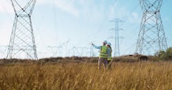 Surveyors inspect transmission lines in a field. Photo from Getty Images Surveyors inspect transmission lines in a field. Photo from Getty Images