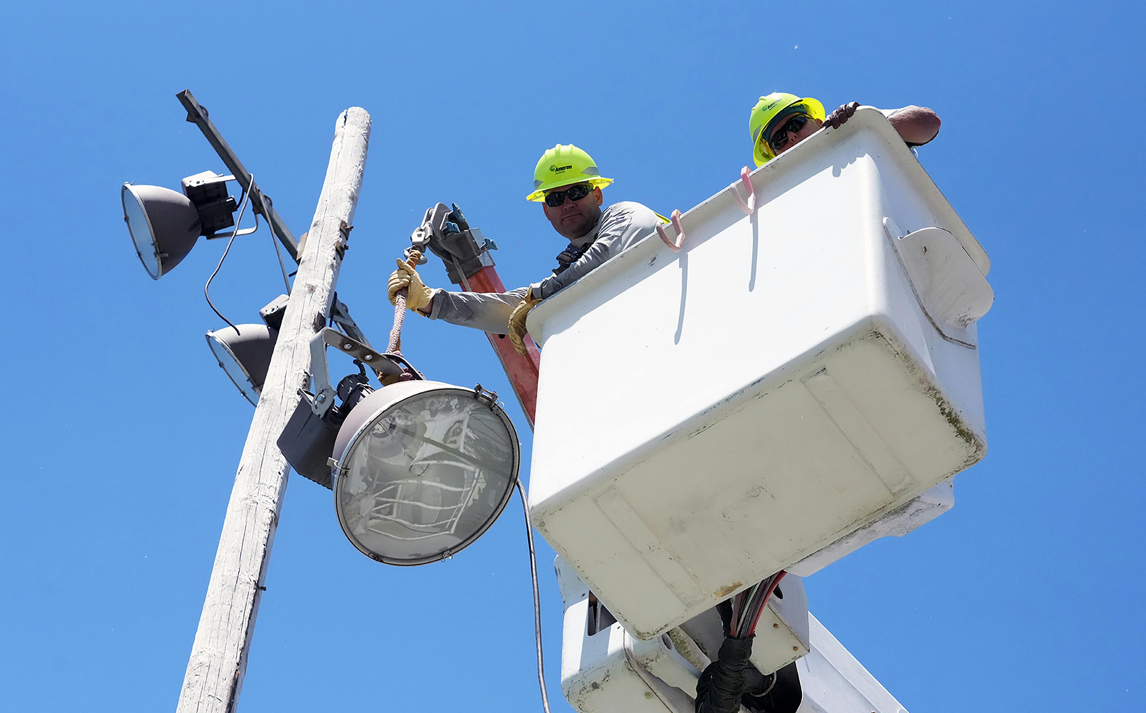 Darren Hess and Mike Blackburn of Ameren Illinois safely remove the olds lights near the tennis courts at Lincoln Park. Once the lights were removed the Ameren Illinois team carefully cut the wooden poles in pieces and safely lowered the pieces to the ground.