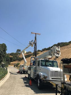 Utility crews perform installation work on a distribution line. Utility crews perform installation work on a distribution line.