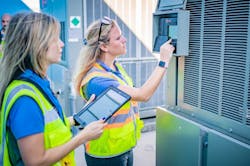 Engineers configuring controllers next to HVAC equipment at a school to optimize energy Engineers configuring controllers next to HVAC equipment at a school to optimize energy
