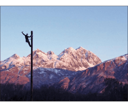 A line worker on a pole with Alaskan scenery. A line worker on a pole with Alaskan scenery.
