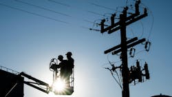 lineworkers in front of light lineworkers in front of light