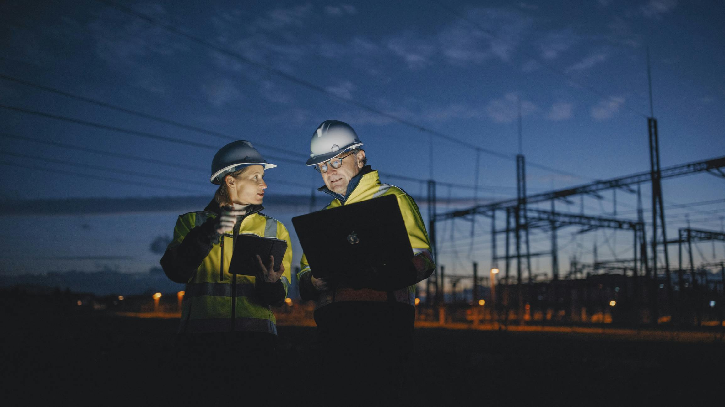 engineers on laptops in front of substation