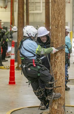 Enrique Garcia, training instructor at ComEd Chicago Training Center, coaches a Women’s Climb Clinic participant as she climbs a practice utility pole. Enrique Garcia, training instructor at ComEd Chicago Training Center, coaches a Women’s Climb Clinic participant as she climbs a practice utility pole.