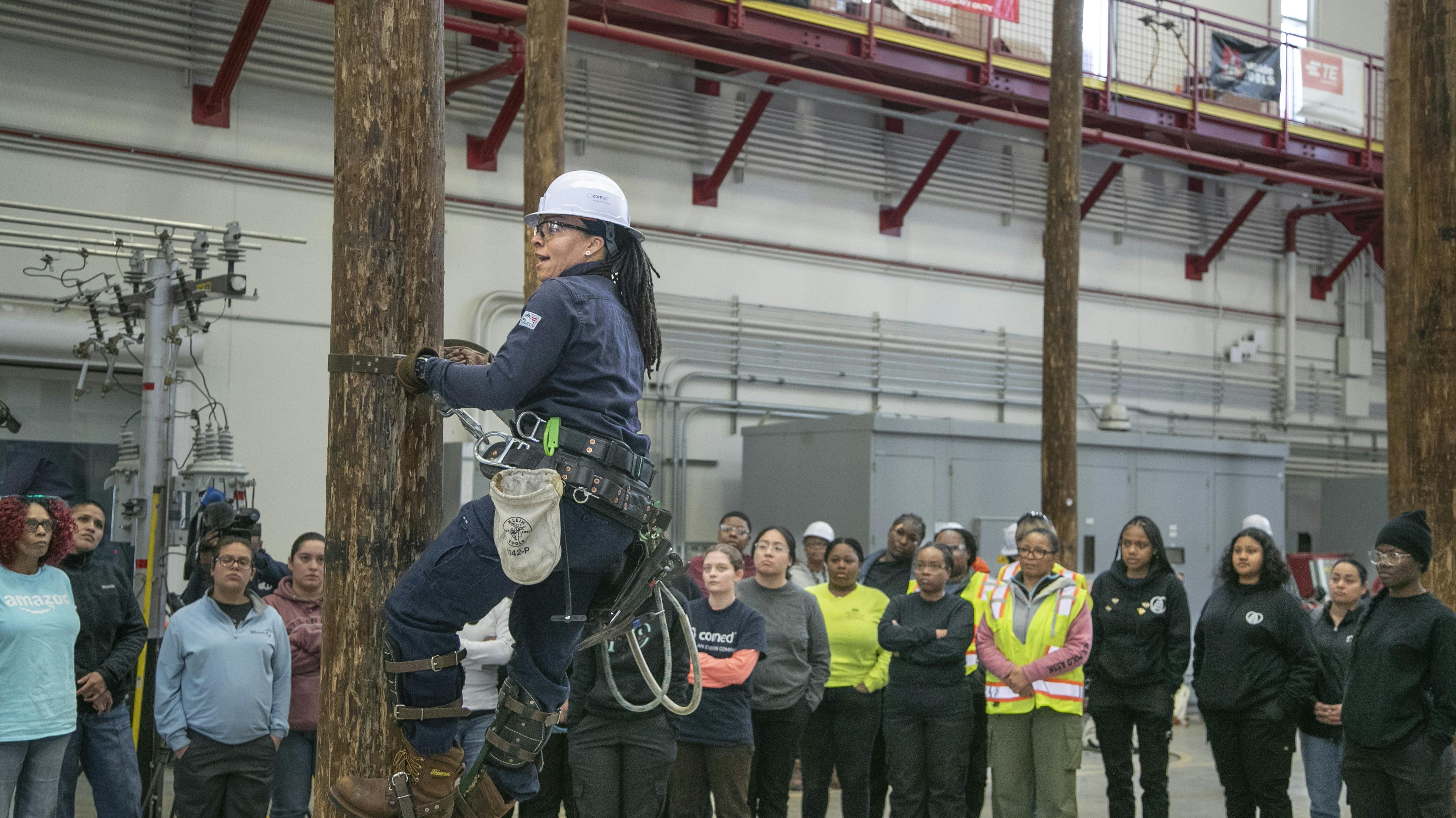 Andrea Simmons, ComEd crew leader, demonstrates how to climb a utility pole to participants of a March 2025 Women&rsquo;s Climb Clinic for a first-hand look at what it takes to join the electrical trades.