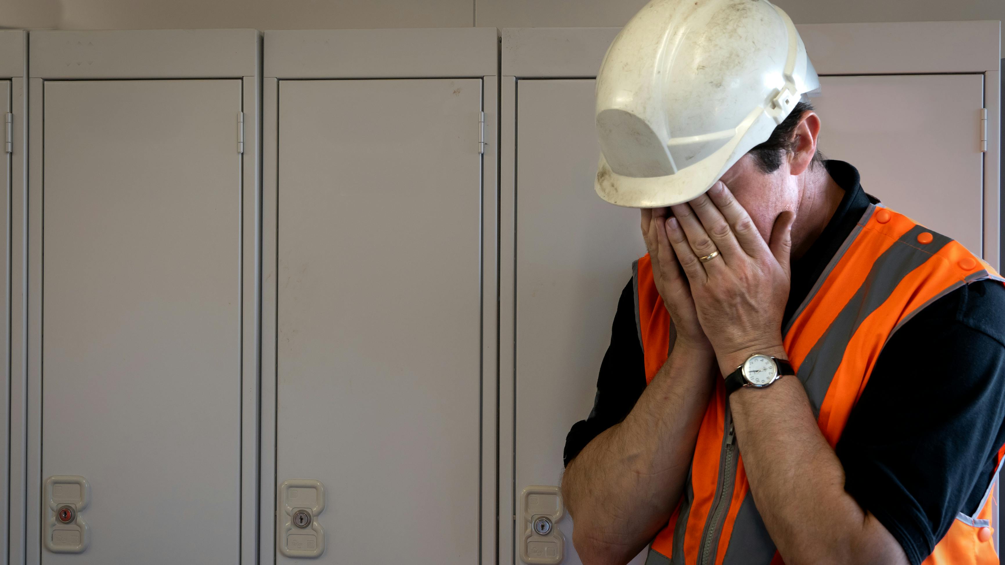 man in hard hat with face in hands