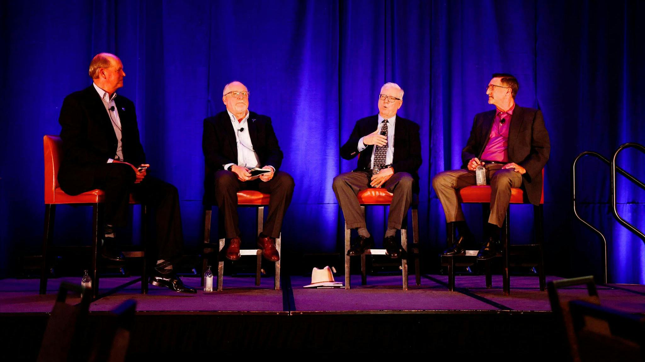 speakers sitting in chairs on stage