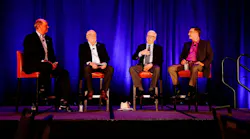 speakers sitting in chairs on stage