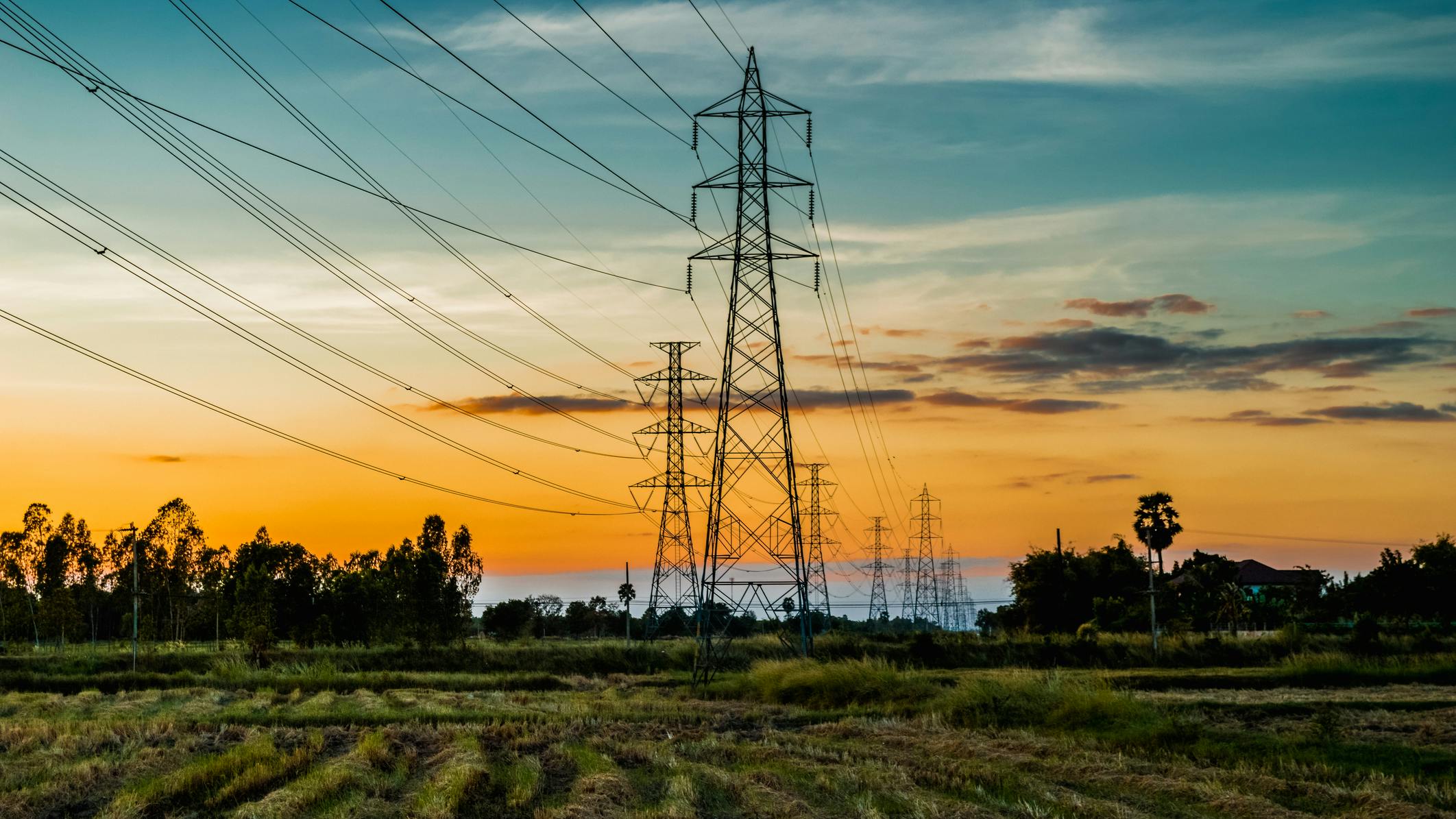High voltage AC transmission towers during sunset time on Prairie
