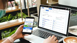hand holding phone with app in front of computer